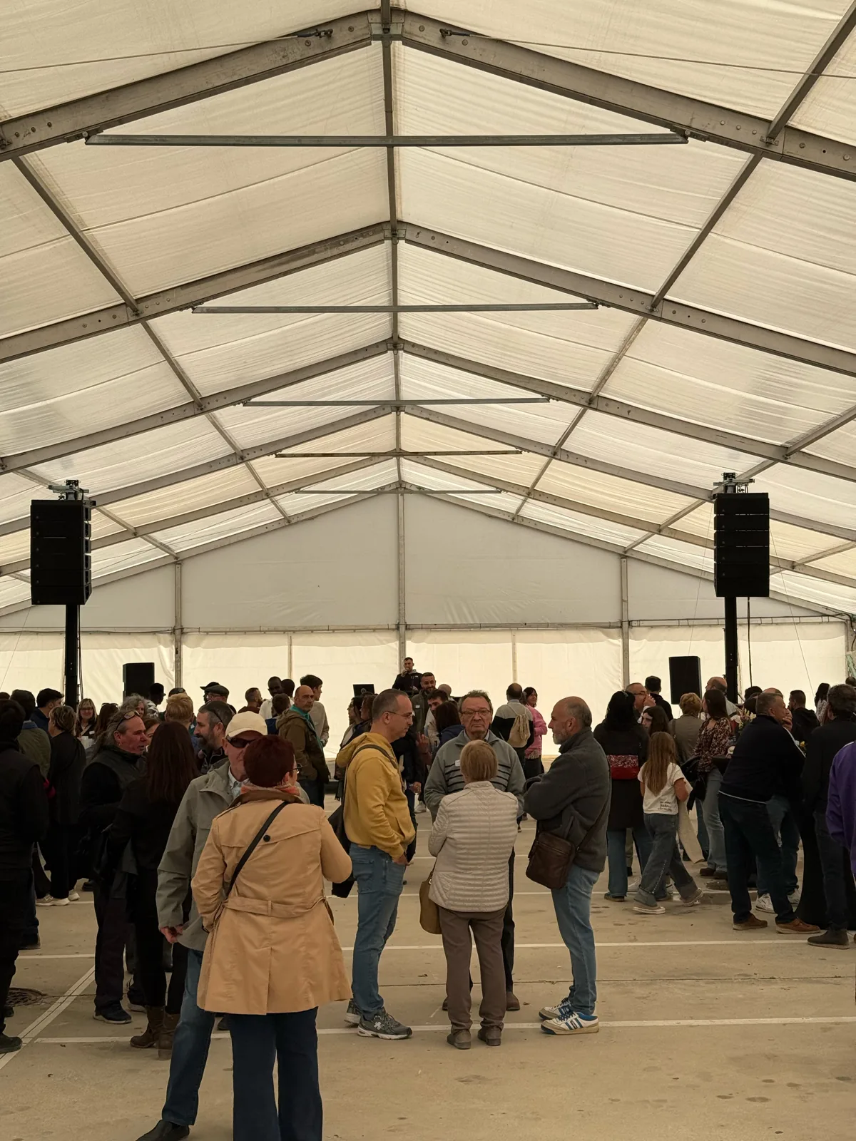 Sistema Adamson de Edersound suspendido a ambos lados de una carpa durante un evento con público.